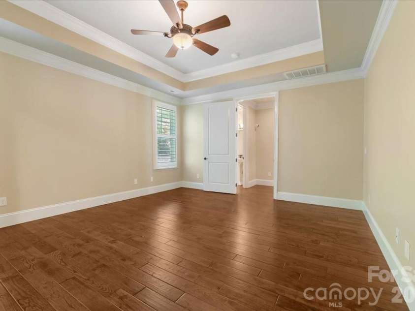 7304 Sedgebrook Drive, Stanley, NC 28164.  MLS# CAR4372754, YatesRealty ID 20028. Another angle, same story — this primary bedroom was designed with intention from every corner. Tray ceiling, engineered hardwoods, and natural light that fills the room without a single unwanted view to interrupt it.