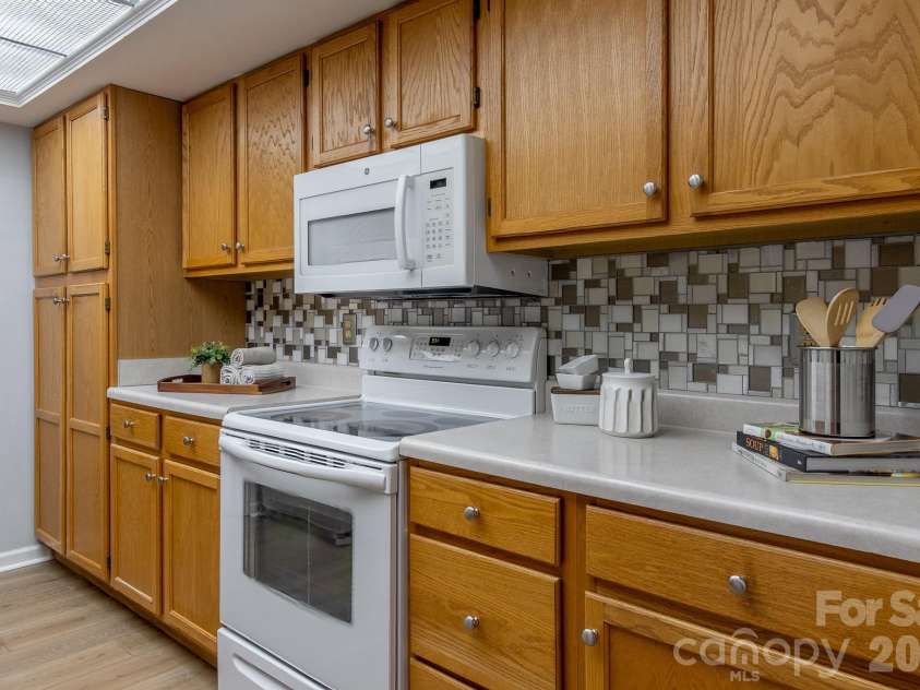 304 Emerald Hills Drive, Pisgah Forest, NC 28768.  MLS# CAR4373958, YatesRealty ID 20076. Kitchen Detail – Additional kitchen view featuring abundant oak cabinetry, updated backsplash accents, and generous countertop workspace. Functional galley layout offers excellent storage and efficiency.