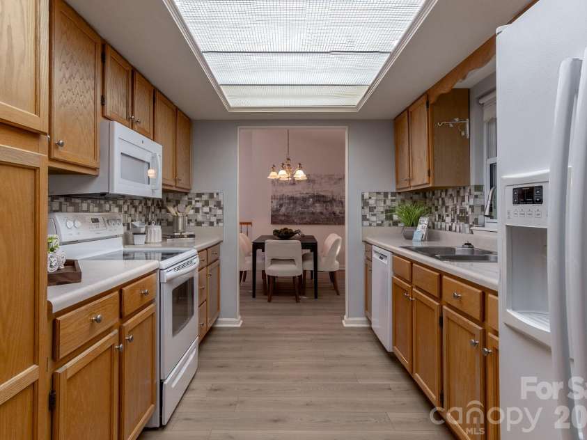 304 Emerald Hills Drive, Pisgah Forest, NC 28768.  MLS# CAR4373958, YatesRealty ID 20076. Kitchen – Galley-style kitchen with abundant cabinet storage, updated backsplash, and ample countertop workspace. Bright overhead lighting and an efficient layout make meal prep simple and convenient.