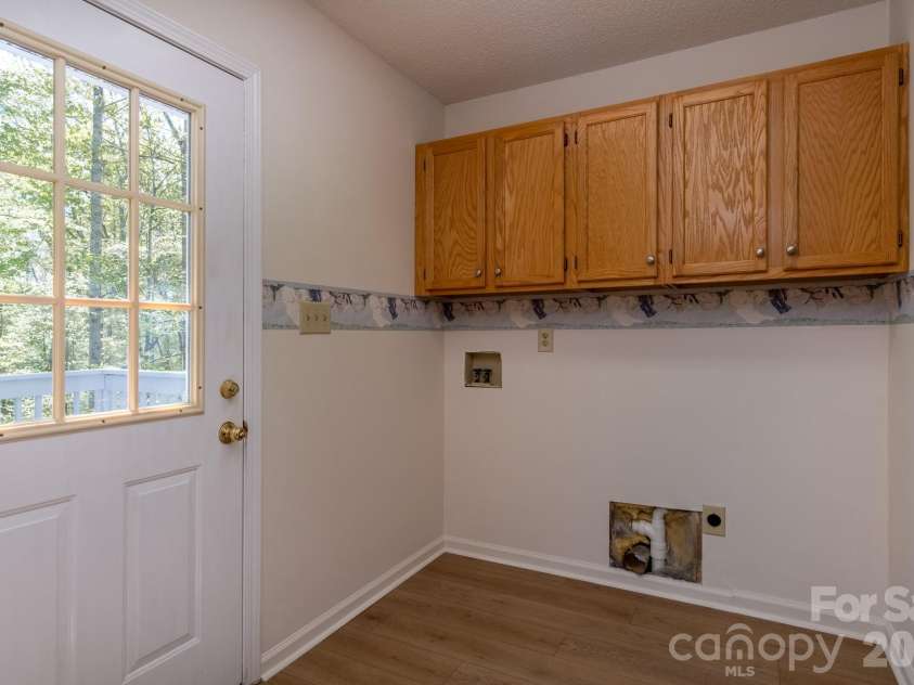 304 Emerald Hills Drive, Pisgah Forest, NC 28768.  MLS# CAR4373958, YatesRealty ID 20076. Laundry Room – Dedicated laundry space with upper cabinetry for storage and direct exterior access, adding everyday convenience.