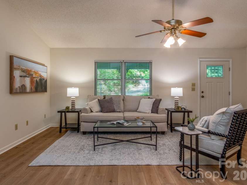 304 Emerald Hills Drive, Pisgah Forest, NC 28768.  MLS# CAR4373958, YatesRealty ID 20076. Living Room – Comfortable living room with oversized front-facing windows, neutral finishes, and plenty of space for seating and gathering. The open layout creates a bright and inviting feel throughout the main