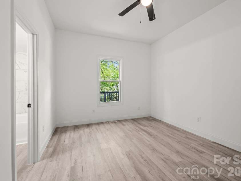 26 Poe Street, Rock Hill, SC 29730.  MLS# CAR4377637, YatesRealty ID 20117. The primary suite offers a serene retreat with LVP flooring and a large window overlooking the back deck and lush greenery. This view also showcases the convenient, direct access to the private ensuite bathroom featuring ele