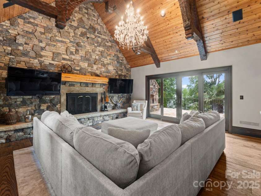 172 Tennessee Circle, Mooresville, NC 28117.  MLS# CAR4252701, YatesRealty ID 20154. Living Room with stone fireplace, dual TVs, and doors to outdoor patio.