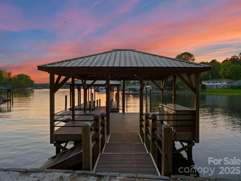 172 Tennessee Circle, Mooresville, NC 28117.  MLS# CAR4252701, YatesRealty ID 20154. The private dock features covered boat storage, two jet ski ports, an island with built-in storage and mini-fridge, ceiling fans, and a sand-lined lounging area along the water’s edge.