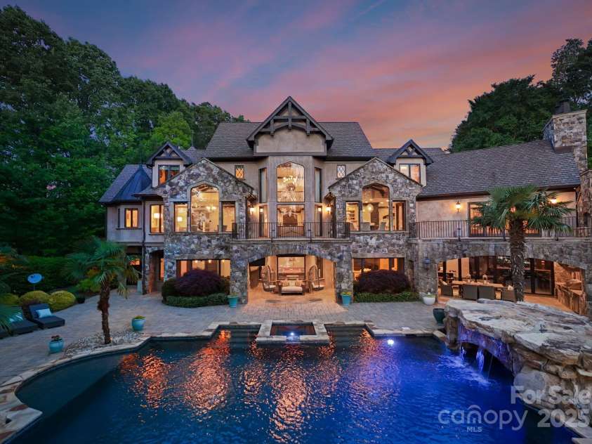 172 Tennessee Circle, Mooresville, NC 28117.  MLS# CAR4252701, YatesRealty ID 20154. Tiered backyard with infinity-edge pool, two covered patios for dining and lounging, and stone pathways leading to the private dock.
