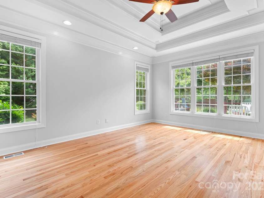 9112 Butterfly Court, Gastonia, NC 28056.  MLS# CAR4267047, YatesRealty ID 20271. Freshly painted Primary Bedroom on Main Floor is bright and expansive with Double Trey Ceiling featuring soft uplighting. It overlooks the lovely landscaped back yard.