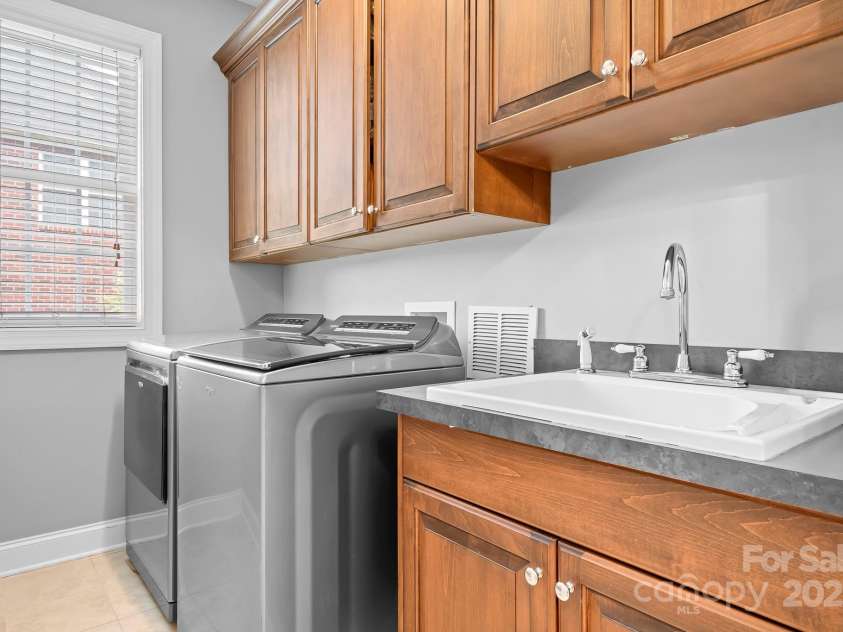 9112 Butterfly Court, Gastonia, NC 28056.  MLS# CAR4267047, YatesRealty ID 20271. Laundry Room directly off of garage with Whirlpool Top Load Washer and Whirlpool Smart Capable Steam Cycle vented Electric Dryer conveying. On the other wall is a folding table that folds down flat maximizing the space