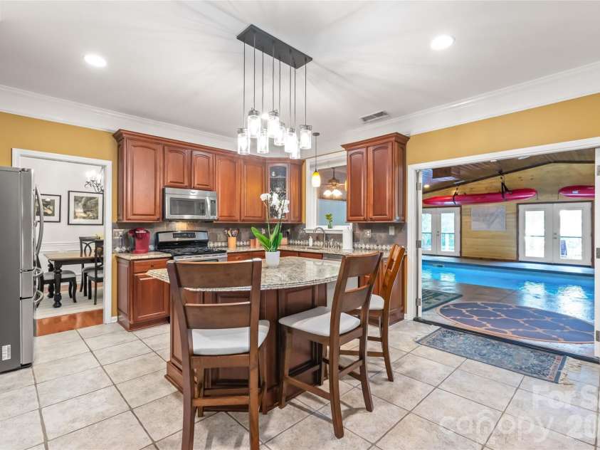 13934 Kings Carriage Lane, Charlotte, NC 28278.  MLS# CAR4424593, YatesRealty ID 20305. Beautiful cabinetry adds ample storage. Granite with tile backsplash adds style. Double doors lead to the climate controlled pool area
