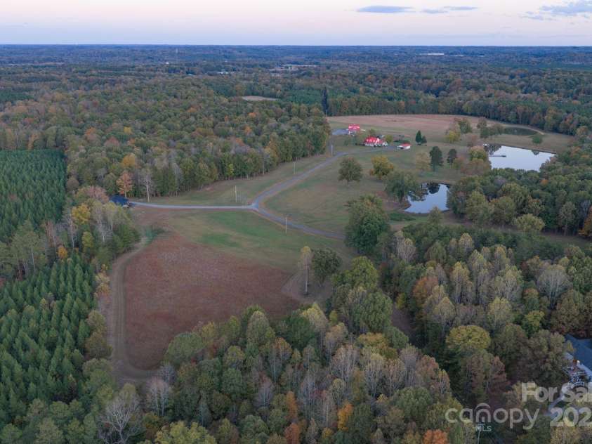 1260 Beaver Island Trail Road, Walnut Cove, NC 27052.  MLS# CAR4325171, YatesRealty ID 2036. Aerial shot of open pasture land, 3 stocked pond, private driveway, wooded areas, and guest house seclusion from the main farm house.