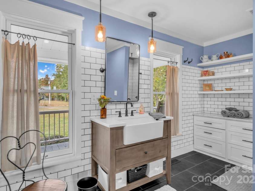 1260 Beaver Island Trail Road, Walnut Cove, NC 27052.  MLS# CAR4325171, YatesRealty ID 2036. Primary en-suite bathroom w/ farmhouse vanity w/ quartz countertop, frameless glass door and floor-to-ceiling tile shower, built in dresser vanity, & large deep wall closet