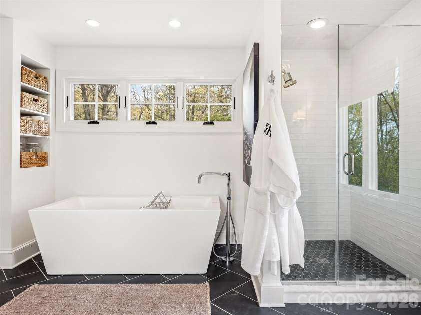 10 Kalimar Heights, Hendersonville, NC 28739.  MLS# CAR4376746, YatesRealty ID 20362. Elegant light filled primary bath with a freestanding soaking tub, frameless glass walk-in shower, and clean, modern finishes throughout.