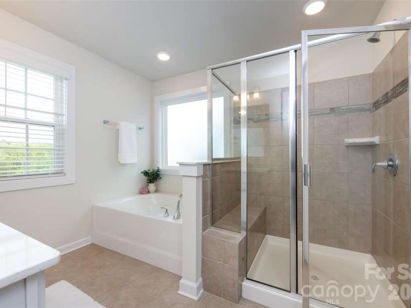 11440 Westbranch Parkway, Davidson, NC 28036.  MLS# CAR4366825, YatesRealty ID 20419. Spacious primary bath featuring dual vanities, a soaking tub, and a separate glass-enclosed shower for a spa-like retreat.