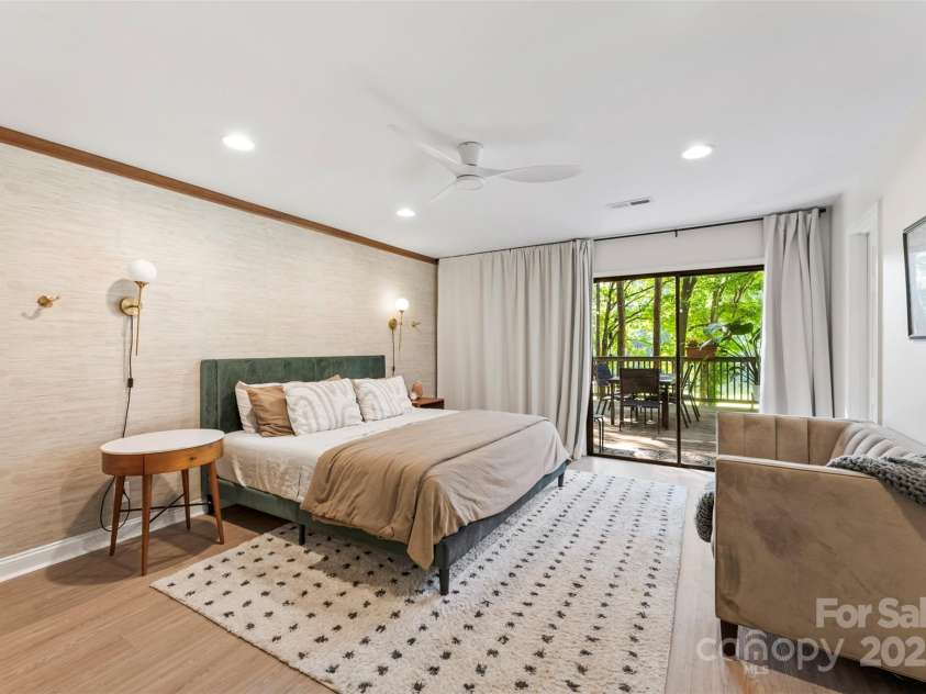 50 Honeysuckle Woods, Lake Wylie, SC 29710.  MLS# CAR4254838, YatesRealty ID 20638. Well appointed primary bedroom on main complimented with grasscloth wallpaper, sconce lighting and private deck space.