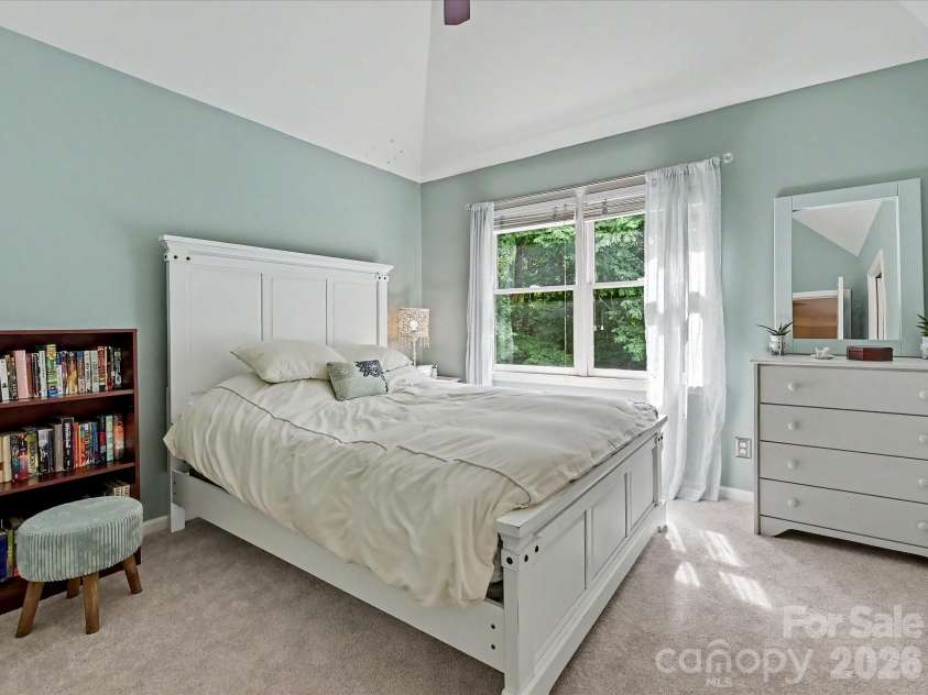 17405 Lynx Den Court, Davidson, NC 28036.  MLS# CAR4377973, YatesRealty ID 20726. Bright and inviting bedroom featuring vaulted ceilings, soft natural light, and a peaceful view of the private, tree-lined backyard.