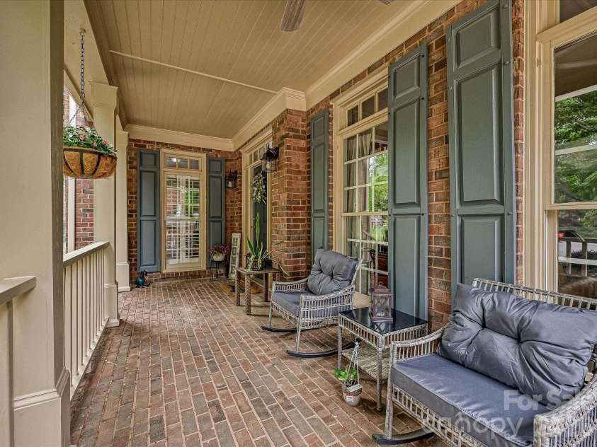 17405 Lynx Den Court, Davidson, NC 28036.  MLS# CAR4377973, YatesRealty ID 20726. Charming covered front porch with classic brick flooring and ample seating space, perfect for relaxing and enjoying the peaceful, tree-lined surroundings.