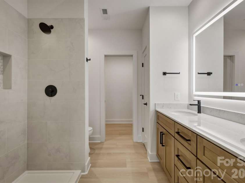173 Waters Edge Drive, Nebo, NC 28761.  MLS# CAR4364596, YatesRealty ID 20742. Here is the fourth bathroom through that barn door. It features a dual sink, a lighted anti fog mirror, and a glass shower enclosure (not installed yet but coming).