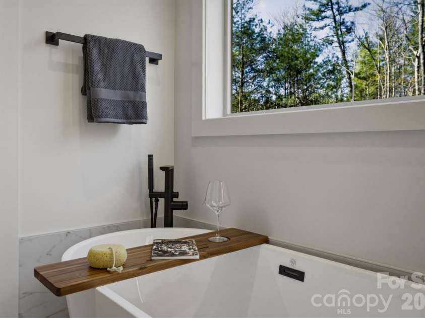 173 Waters Edge Drive, Nebo, NC 28761.  MLS# CAR4364596, YatesRealty ID 20742. Perhaps the most extravagant piece in the bathroom is this freestanding 5' tub under a huge window, and there is even a freestanding tub filler. It will be the perfect spot to relax.