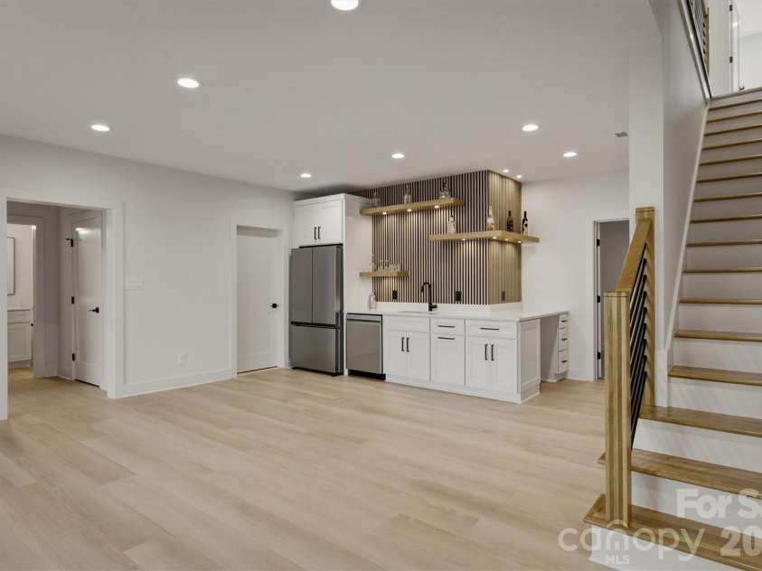 173 Waters Edge Drive, Nebo, NC 28761.  MLS# CAR4364596, YatesRealty ID 20742. The staircase leads to this lower lounge area with plenty of room for furniture. There is a wet bar with a full size refrigerator, a sink, and a dishwasher.