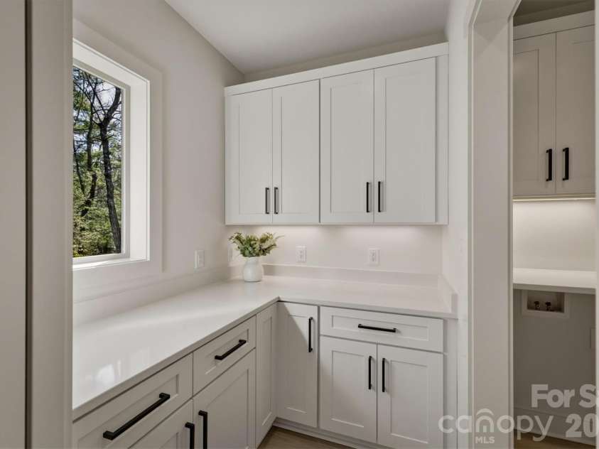 173 Waters Edge Drive, Nebo, NC 28761.  MLS# CAR4364596, YatesRealty ID 20742. The walk-in pantry has a charming window and lots of cabinetry for storage and tons of quartz counter space to work. There is a door into the laundry room on the right.