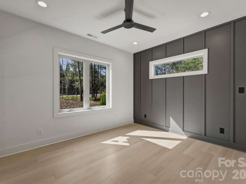 173 Waters Edge Drive, Nebo, NC 28761.  MLS# CAR4364596, YatesRealty ID 20742. To the left of the front door, there is a guest bedroom, Suite 2.. There is a Minka-Aire ceiling fan, and a feature wall with a transom window over the bedspace.