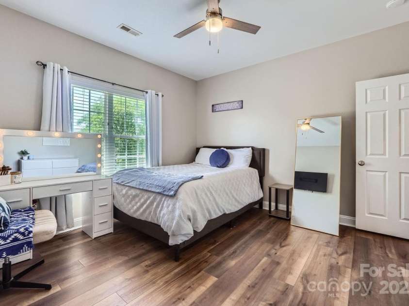 113 Dairy Farm Road, Mooresville, NC 28115.  MLS# CAR4262731, YatesRealty ID 20820. This bright and airy secondary bedroom offers a serene retreat with modern comforts. Rich vinyl plank flooring contrasts beautifully with soft neutral walls, while a large window fills the space with natural light. A