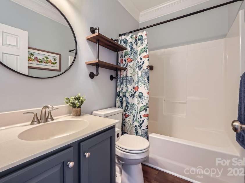 113 Dairy Farm Road, Mooresville, NC 28115.  MLS# CAR4262731, YatesRealty ID 20820. This charming full bathroom combines playful design with practical features. A deep navy vanity with brushed nickel hardware adds a bold, modern touch, while the neutral countertop and sleek undermount sink offer tim