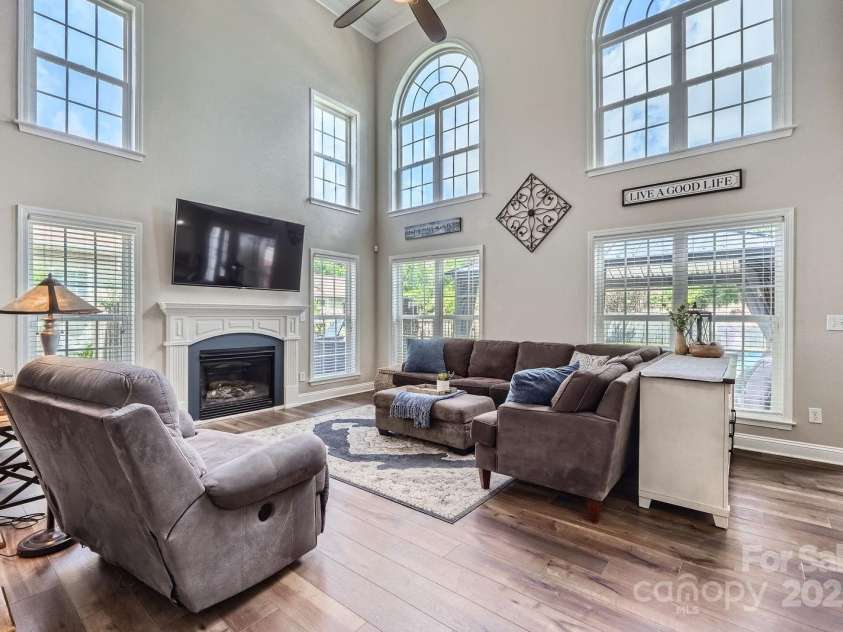113 Dairy Farm Road, Mooresville, NC 28115.  MLS# CAR4262731, YatesRealty ID 20820. Warm-toned luxury vinyl flooring adds richness underfoot, while the wrought iron railing above adds a custom architectural touch. Views of the backyard and pool area enhance the indoor-outdoor feel, making this space