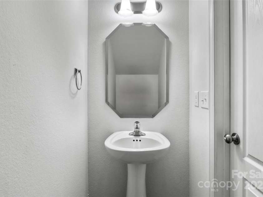 2532 Blue Moss Drive, Dallas, NC 28034.  MLS# CAR4271917, YatesRealty ID 21069. Half bath on main floor of home features a pedestal sink, decorative mirror, freshly painted walls and ceiling, LVP flooring.