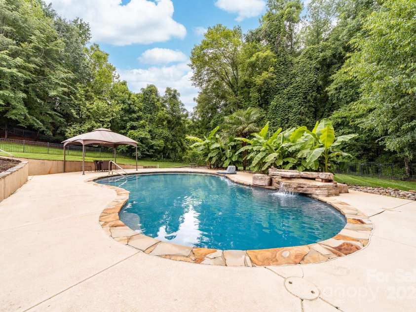 12002 Cobham Court, Huntersville, NC 28078.  MLS# CAR4269076, YatesRealty ID 21134. Beautiful pool with banana trees and a waterfall