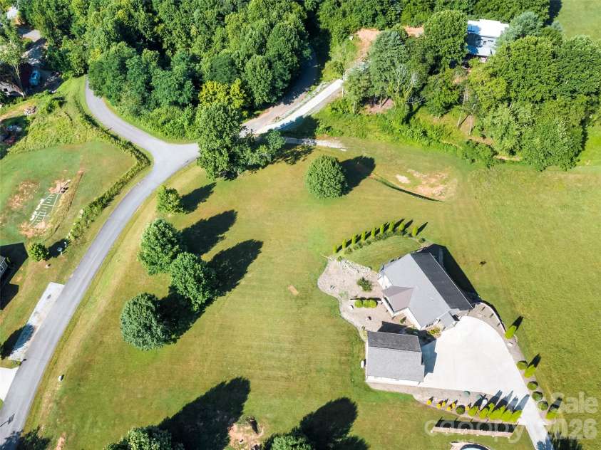141 Round Top Circle, Mills River, NC 28759.  MLS# CAR4379751, YatesRealty ID 21136. Drone photography highlights the lower-level access, ample parking, and versatile outdoor space, showcasing the endless possibilities this property offers.