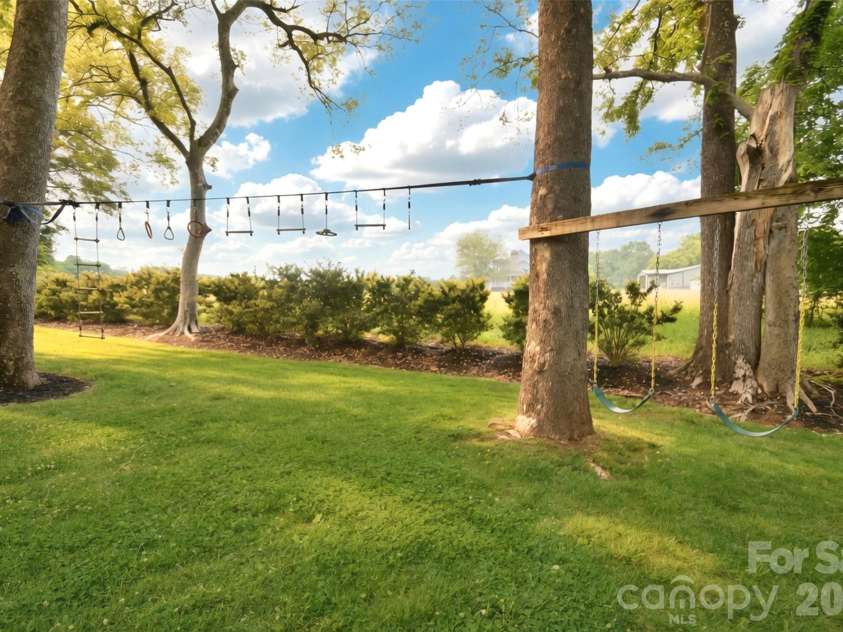 4484 Ranchway Drive, Concord, NC 28027.  MLS# CAR4375185, YatesRealty ID 21305. Charming tree-lined play area with built-in swing set, creating a fun and inviting outdoor space for all ages