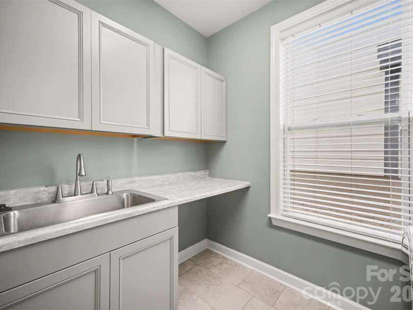 115 Boxelder Road, Clover, SC 29710.  MLS# CAR4364422, YatesRealty ID 21324. Laundry room with tile flooring, washer/dryer remain, upper cabinetry, utility sink with cabinet and folding area 