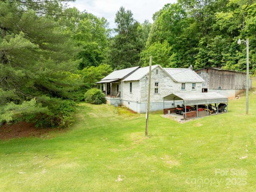 2023 White Springs Lane, Lenoir, NC 28645.  MLS# CAR4266812, YatesRealty ID 21383. Front and side view of farmhouse, detached carport, and storage building
