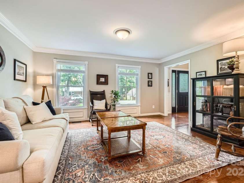 1175 18th Avenue, Hickory, NC 28601.  MLS# CAR4267840, YatesRealty ID 21483. This inviting living room is bathed in natural light from large, double-hung windows that frame serene views of the front yard. Crisp crown molding, wide baseboards, and decorative trim create a sense of timeless elegance, 