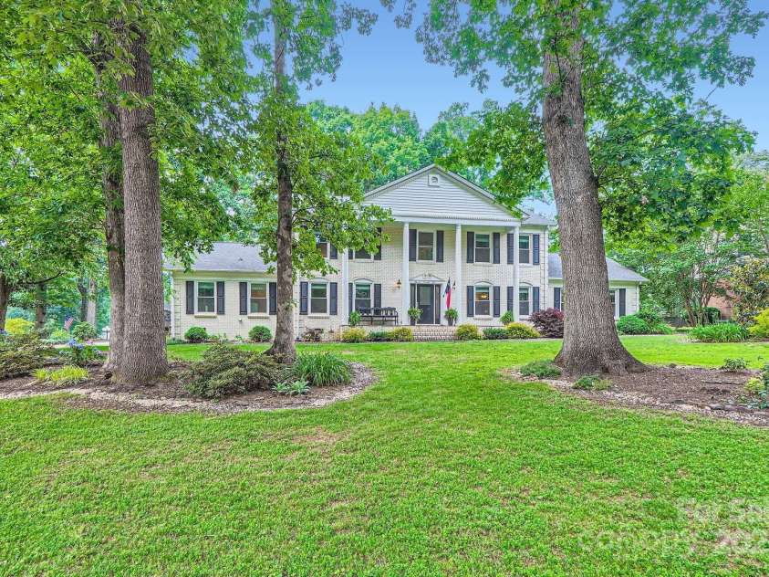 1175 18th Avenue, Hickory, NC 28601.  MLS# CAR4267840, YatesRealty ID 21483. Welcome to this stately brick colonial nestled on a serene, wooded lot. From the moment you arrive, the timeless architecture makes a bold statement with its symmetrical façade, black shutters, and grand two-story columned 