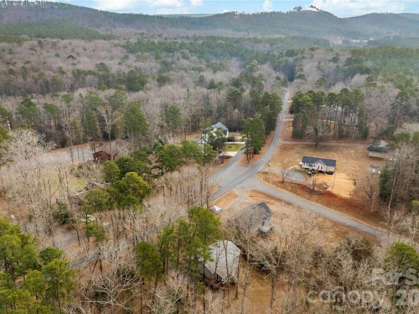 213 Woodrun Drive, Mount Gilead, NC 27306.  MLS# CAR4334949, YatesRealty ID 2158. Aerial view highlights the home’s peaceful setting within a scenic lake community surrounded by natural beauty.