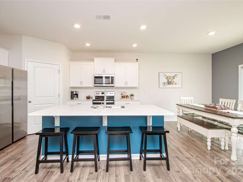 128 Hickory Ridge Drive, Locust, NC 28097.  MLS# CAR4270614, YatesRealty ID 21621. Large kitchen with island, granite countertop, tile backsplash, stainless steel appliances and LVP flooring.