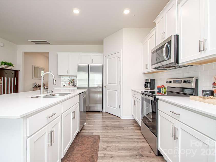 128 Hickory Ridge Drive, Locust, NC 28097.  MLS# CAR4270614, YatesRealty ID 21621. Large kitchen with island, granite countertop, tile backsplash, stainless steel appliances and LVP flooring.