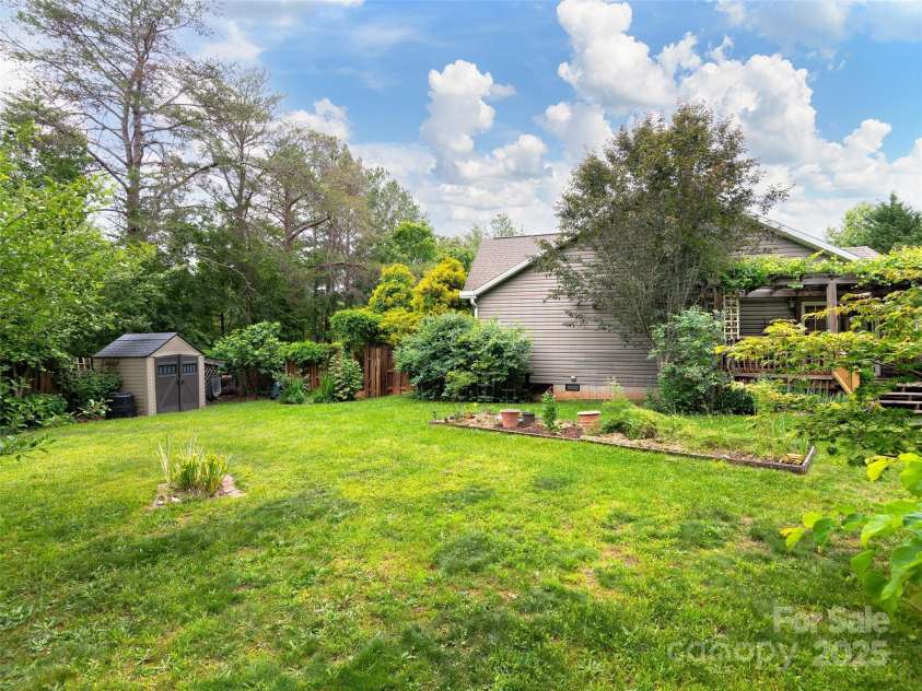 224 Old Haw Creek Road, Asheville, NC 28805.  MLS# CAR4259478, YatesRealty ID 21638. From Fire Pit looking across yard where a smaill shed is handy for garden tools, and a gate leads to the front yard and entry to the home.