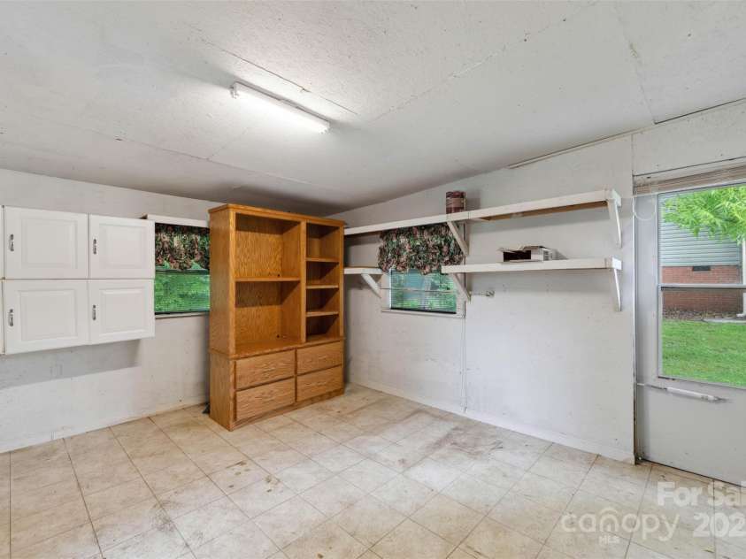 46 Donna Dale Avenue, Concord, NC 28025.  MLS# CAR4268171, YatesRealty ID 21700. Large storage room off the carport with view of added cabinets and shelves with a separate side door leading out to the extra parking area