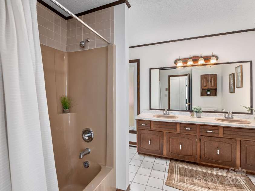 1469 Old Fort Road, Fairview, NC 28730.  MLS# CAR4240790, YatesRealty ID 21774. Primary bathroom with wood cabinets, double sink vanity and ceramic tile floors