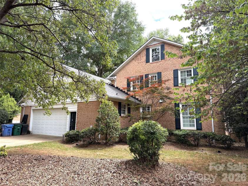 2530 Weathersford Road, Mint Hill, NC 28227.  MLS# CAR4376726, YatesRealty ID 21798. Side elevation featuring a sideload garage, classic brick exterior, and numerous windows with shutters, enhancing both curb appeal and natural light throughout the home.