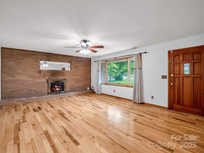 989 Mine Gap Road, Zirconia, NC 28790.  MLS# CAR4264634, YatesRealty ID 21834. Living room with gas log fireplace and hardwood floors