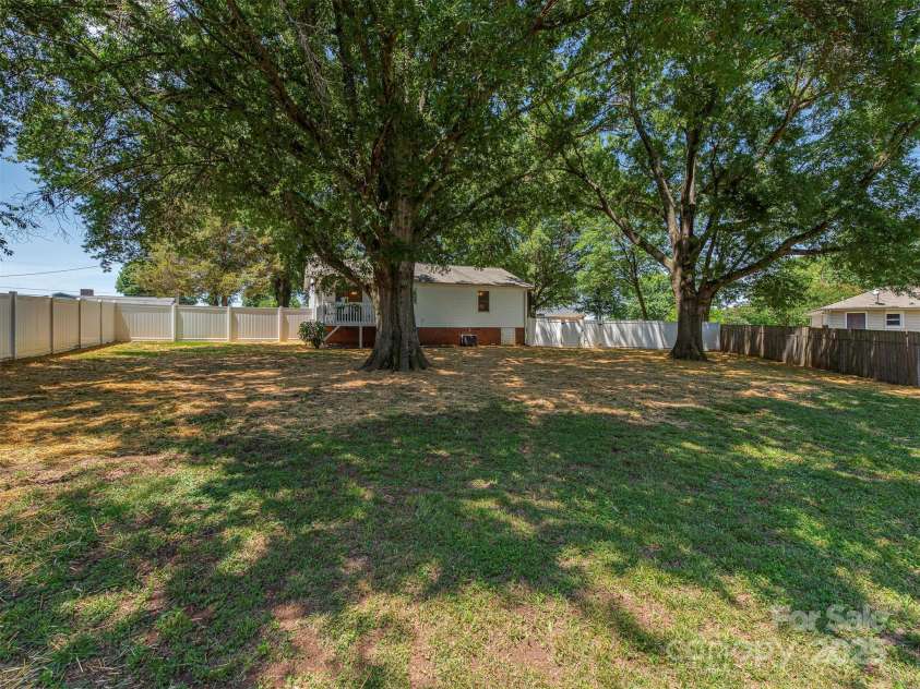 713 Springfield Drive, Concord, NC 28027.  MLS# CAR4269267, YatesRealty ID 22075. In the backyard, two beautiful oak trees provide a lush canopy, anchoring the space with timeless charm and natural shade.