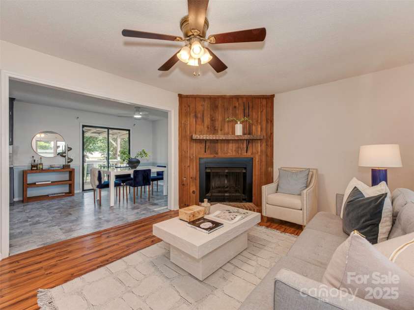 713 Springfield Drive, Concord, NC 28027.  MLS# CAR4269267, YatesRealty ID 22075. This beautifully wood-toned living room, anchored by a cozy corner fireplace, flows effortlessly into the kitchen and dining area—perfect for relaxed gatherings and effortless entertaining.