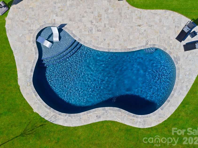 1053 Harlow's Crossing Drive, Matthews, NC 28104.  MLS# CAR4353232, YatesRealty ID 22111. Overhead view of custom-shaped pool with travertine decking