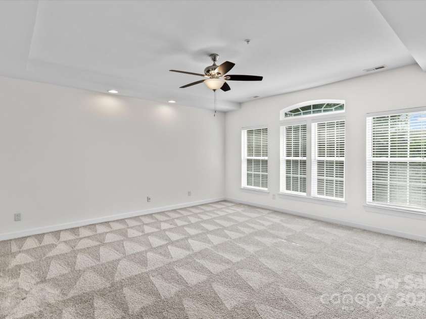 1530 Church Street, Charlotte, NC 28203.  MLS# CAR4259116, YatesRealty ID 22130. Primary bedroom suite with tray ceiling, fan, and abundant windows facing a private rear of the condo.