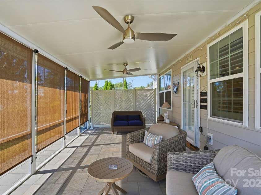 1224 Dali Boulevard, Mount Holly, NC 28120.  MLS# CAR4274726, YatesRealty ID 22189. Interior of screened porch with two ceiling fans with lights and privacy shades.