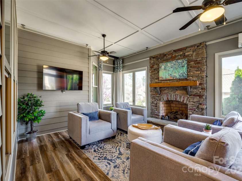 15620 Lake Ridge Road, Charlotte, NC 28278.  MLS# CAR4238155, YatesRealty ID 22515. Embrace the beauty of all four seasons in this inviting sunroom, where natural light floods in and the warmth of a stone fireplace creates a cozy atmosphere.
