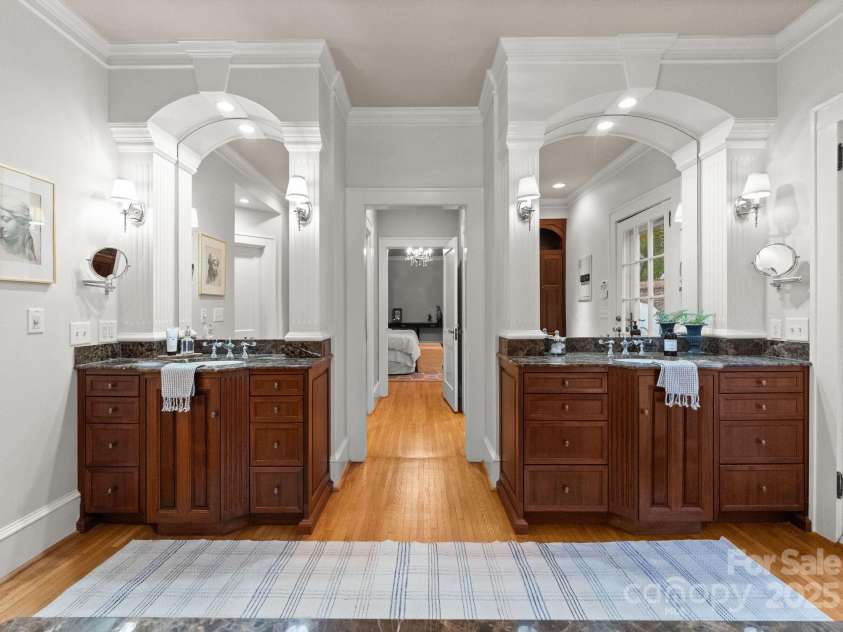 215 Main Street, Belmont, NC 28012.  MLS# CAR4134774, YatesRealty ID 22545. Double custom-made mahogany vanities have lots of storage with ceramic sink, Kohler faucets,  and large curved mirrors with down lights and sconces. Beautiful wide moldings with arch pediments elevate the classic space!  Not